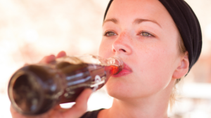 a young woman drinking soda from a bottle of Coca Cola