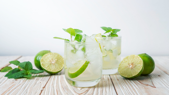 Two glasses with water, lime slices, and sprigs of mint.
